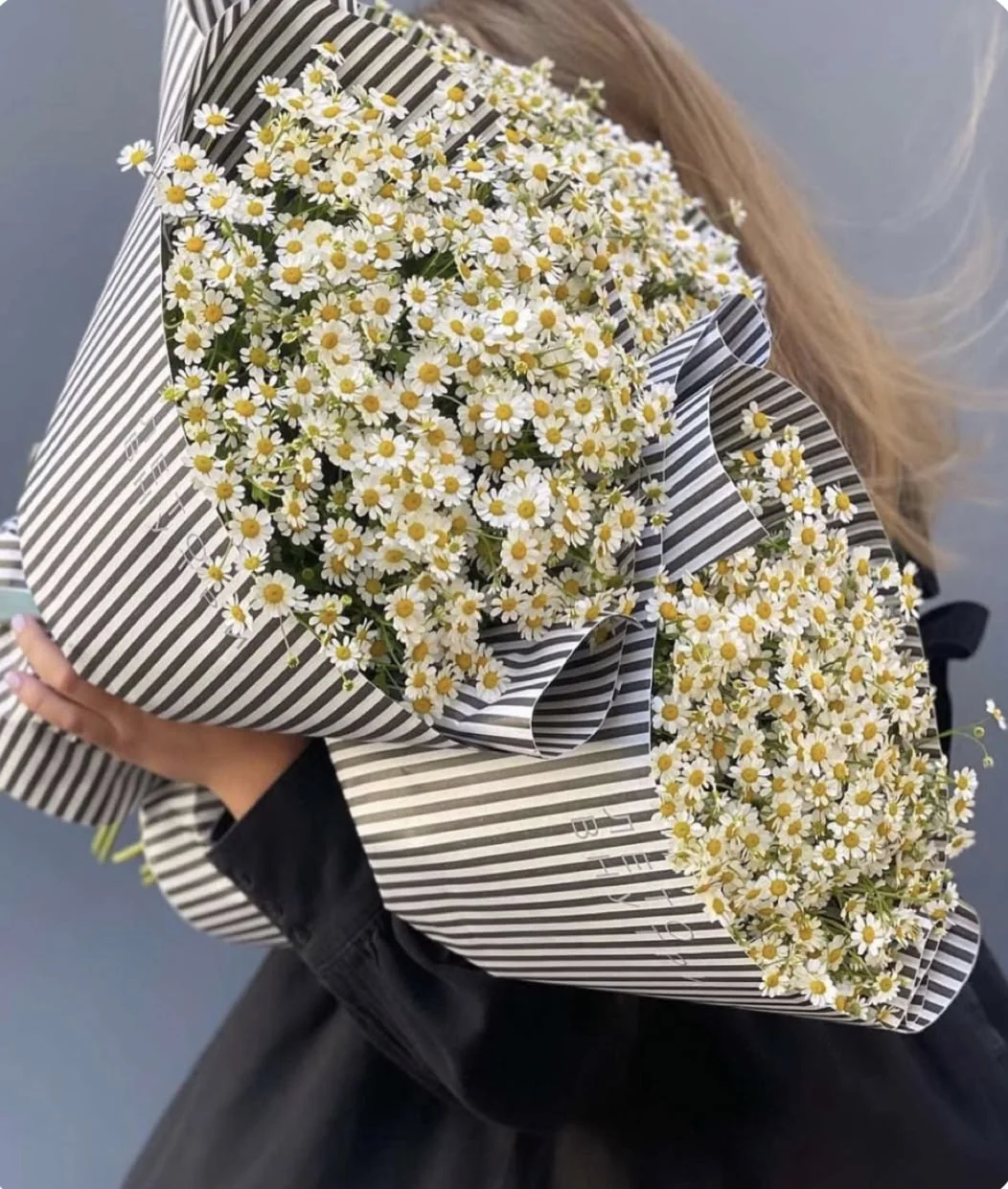 An abundant white flower bundle held against a dark jacket.