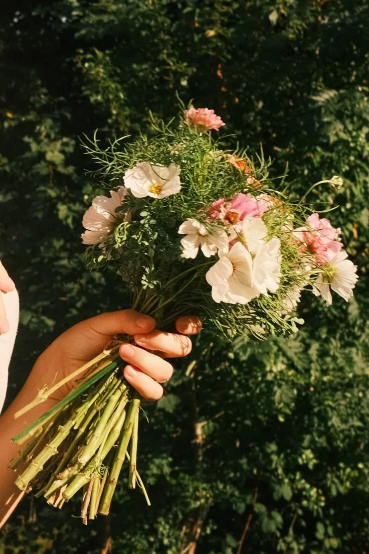 A delicate cream, blush and green garden posy held in woodland light.